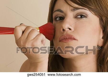 Close-up of a young woman applying blush on her cheek View Large Photo Image Stock Image - Close-up of a young woman applying blush on her cheek. Fotosearch