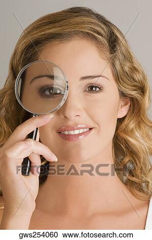 Close-up of a young woman looking through a magnifying glass View Large Photo Image Stock Image - Close-up of a young woman looking through a magnifying glass. Fotosearch