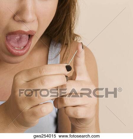 Close-up of a young woman pinching her finger with a needle View Large Photo Image Stock Photography - Close-up of a young woman pinching her finger with a needle. Fotosearch