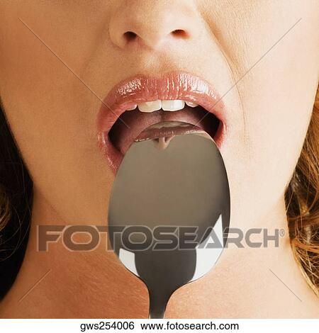 Close-up of a young woman with a spoon in her mouth View Large Photo Image Stock Photograph - Close-up of a young woman with a spoon in her mouth. Fotosearch