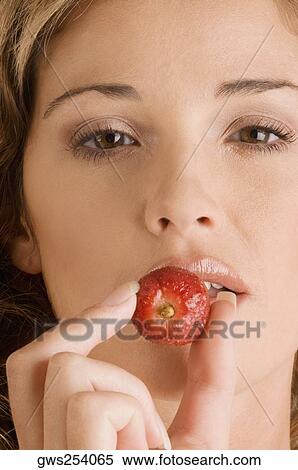Portrait of a young woman eating a strawberry View Large Photo Image Stock Photography - Portrait of a young woman eating a strawberry. Fotosearch