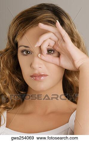 Portrait of a young woman looking through a circle formed by her fingers View Large Photo Image Stock Photo - Portrait of a young woman looking through a circle formed by her fingers. Fotosearch
