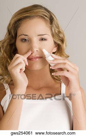 Portrait of a young woman putting nasal spray drops in her nose View Large Photo Image Stock Image - Portrait of a young woman putting nasal spray drops in her nose. Fotosearch