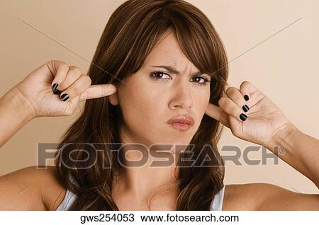 Portrait of a young woman with her fingers in her ears View Large Photo Image Stock Image - Portrait of a young woman with her fingers in her ears. Fotosearch