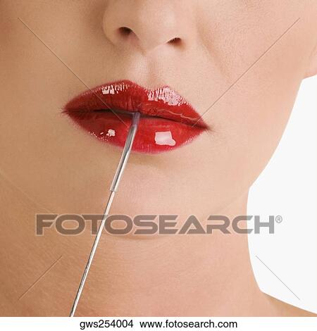 Picture - Young woman applying lipstick. Fotosearch