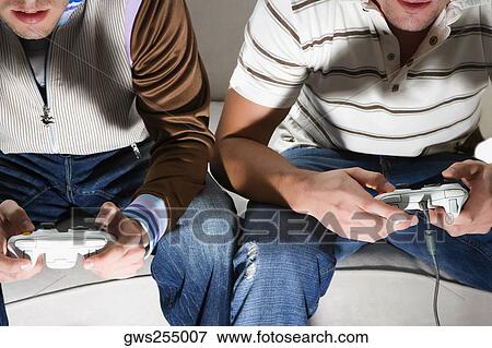 Close-up of two young men playing video game View Large Photo Image Stock Photo - Close-up of two young men playing video game. Fotosearch