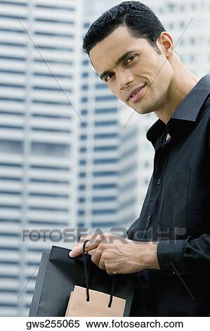 Portrait of a mid adult man holding shopping bags and smiling View Large Photo Image Stock Photography - Portrait of a mid adult man holding shopping bags and smiling. Fotosearch
