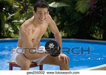 Portrait of a young man exercising with a dumbbell at the poolside View Large Photo Image Stock Image - Portrait of a young man exercising with a dumbbell at the poolside. Fotosearch