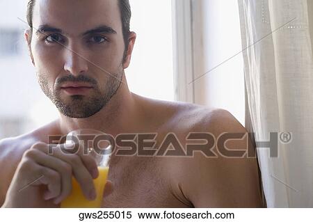 Portrait of a young man holding a glass of juice and thinking View Large Photo Image Stock Photography - Portrait of a young man holding a glass of juice and thinking. Fotosearch