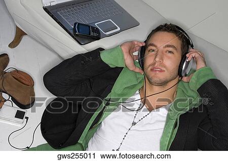 Portrait of a young man listening to an MP3 player View Large Photo Image Stock Image - Portrait of a young man listening to an MP3 player. Fotosearch