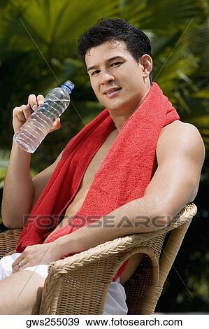 Portrait of a young man sitting on a chair and drinking water View Large Photo Image Stock Photo - Portrait of a young man sitting on a chair and drinking water. Fotosearch