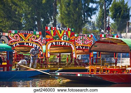 Stock Image - Two men on a trajineras boat, Xochimilco Gardens, Mexico City, Mexico. Fotosearch
