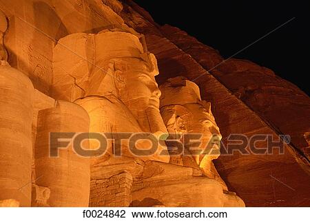 Stock Image - Egypt, Abu Simbel, temple of Ramesses II, statues of Ramesses in profile by night. Fotosearch