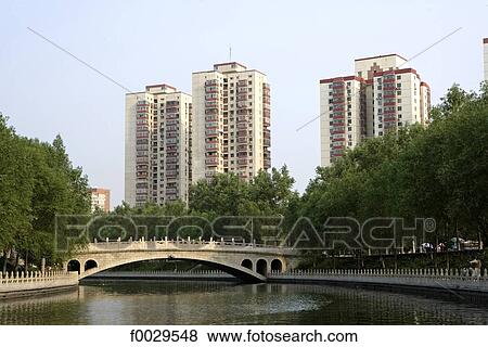 Stock Photo - China, Beijing, canal leading to the Summer Palace, traditional bridge and habitations buildings. Fotosearch