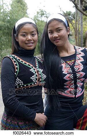 Stock Image - China, Yunnan, near Kunming, Yunnan Nationalities Village, young women wearing traditional costume. Fotosearch