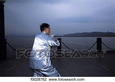 Stock Image - China, Zhejiang, Hangzhou, near the great lake, practising tai-chi. Fotosearch