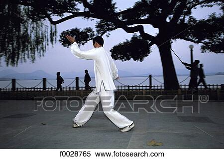 Stock Photography - China, Zhejiang, Hangzhou, near the great lake, practising tai-chi. Fotosearch