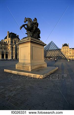 Stock Image - France, Paris, cour Napoléon, equestrian statue of Louis XVI and Louvre Pyramid. Fotosearch