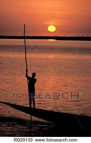 Stock Image - Mali, man on a pirogue at sunset. Fotosearch