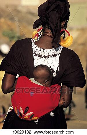 Stock Image - Mali, Mopti, woman carrying her child on her back. Fotosearch