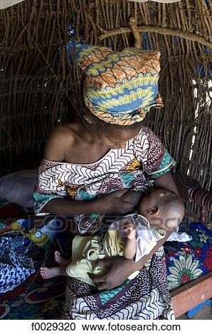 Stock Image - Senegal, Fula village, woman breastfeeding her baby. Fotosearch