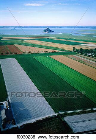 Stock Photo - France, Normandy, Mont Saint-Michel and cultivated fields along the coastline, aerial view. Fotosearch