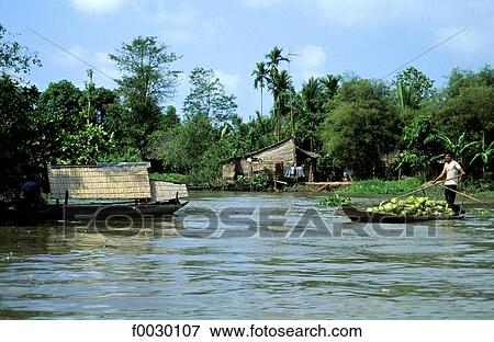 Stock Photo - Vietnam, Mekong delta, wooden huts and boats on Mekong River. Fotosearch
