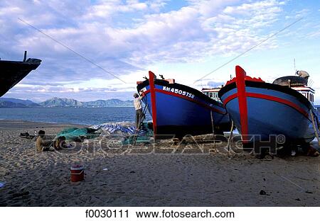 Stock Image - Vietnam, Nha Trang, fisherman repainting his boat. Fotosearch