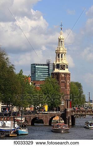Stock Photo - The Netherlands, North Holland, Amsterdam, canal and Montelbaanstoren tower in the background. Fotosearch