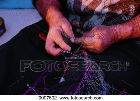 Stock Image - Malta, Marsaxlokk, fisherman mending his nets. Fotosearch