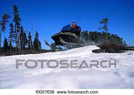 Stock Photograph - Ontario, Sunset, snowbike jump. Fotosearch