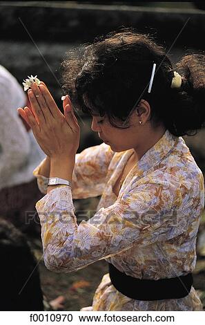 Stock Image - Woman at prayer in Klunkung temple. Fotosearch