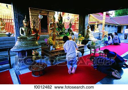 Stock Image - Thailand, Chiang Mai, praying in Wat Doi Suthep temple. Fotosearch