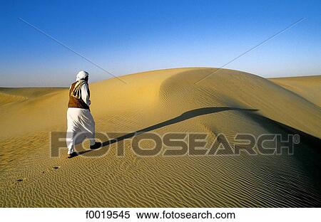 Stock Photography - Egypt, Libyan desert, Beduin walking on a sand dune. Fotosearch