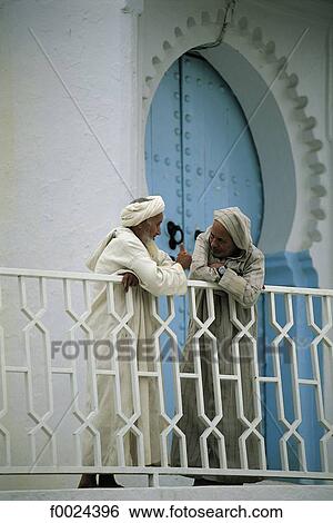 Stock Photograph - Morocco, Chefchaouen, men discussing on a balcony. Fotosearch