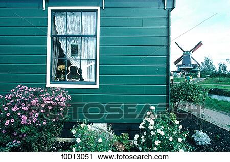 Stock Image - The Netherlands, North Holland, Vollendam, wooden house and windmill. Fotosearch