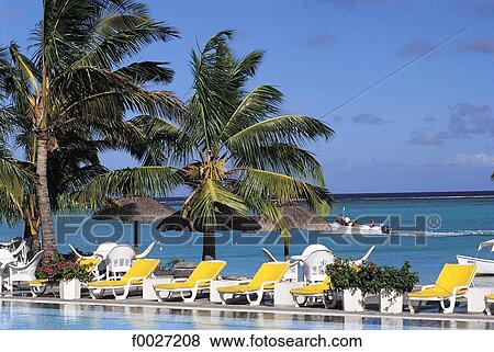Stock Photo - Mauritius, deck chairs by a hotel pool. Fotosearch