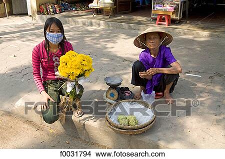 Vietnam, Hoi An, young woman with flowers and seller of vegetables. View Large Photo Image Picture - Vietnam, Hoi An, young woman with flowers and seller of vegetables.. Fotosearch