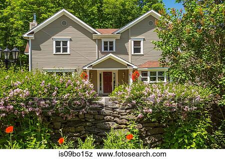 Stock Photo - 1990s Contemporary Victorian style country home facade with hanging baskets and dry stone wall. Fotosearch