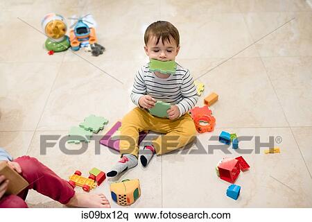 Stock Photography - Baby boy and brother playing with toys on floor. Fotosearch