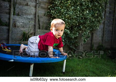Stock Photo - Baby boy crawling on trampoline. Fotosearch