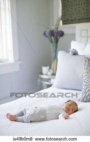 Stock Photo - Baby boy, lying on bed, sleeping. Fotosearch