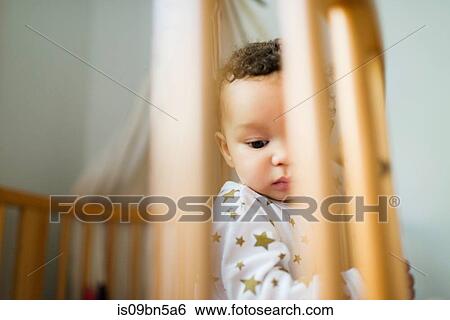 Stock Photograph - Baby boy standing up in crib looking down. Fotosearch