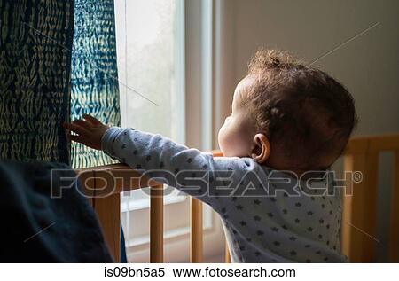 Baby boy standing up in crib looking out through window View Large Photo Image Stock Photography - Baby boy standing up in crib looking out through window. Fotosearch