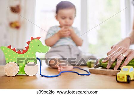 Baby girl sitting on kitchen counter watching mother slicing cucumber View Large Photo Image Picture - Baby girl sitting on kitchen counter watching mother slicing cucumber. Fotosearch