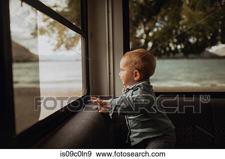 Stock Photo - Baby looking out window of motorhome, Wanaka, Taranaki, New Zealand. Fotosearch