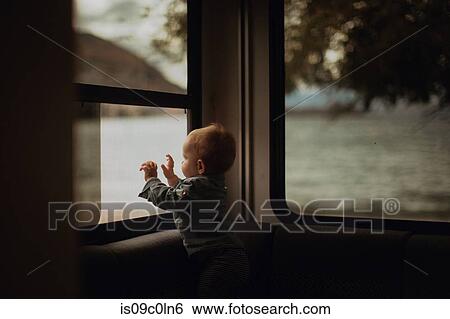 Stock Photograph - Baby looking out window of motorhome, Wanaka, Taranaki, New Zealand. Fotosearch