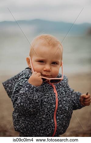 Baby putting on sunglasses on beach View Large Photo Image Picture - Baby putting on sunglasses on beach. Fotosearch