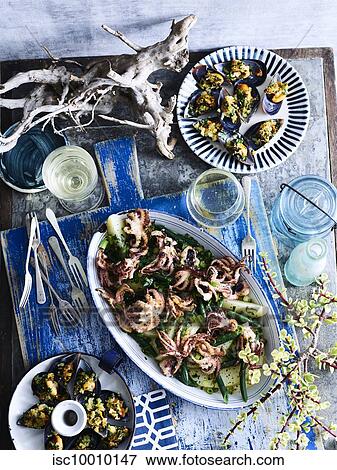 Stock Photo - Baked baby octopus and mussels served with white wine. Fotosearch