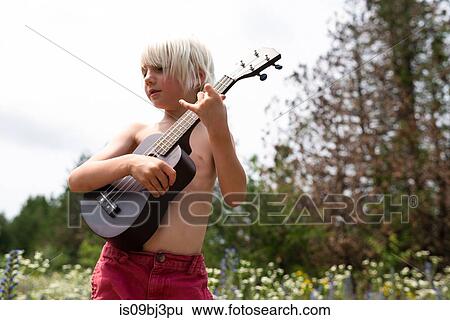 Bare chested blond haired boy playing ukulele in wildflower meadow View Large Photo Image Stock Photograph - Bare chested blond haired boy playing ukulele in wildflower meadow. Fotosearch
